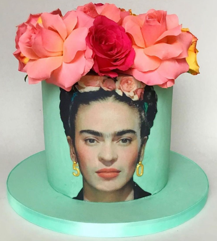 green cake with a printed photo topper of a lady with flowers in her hair. The printed icing sheet is cut out to the shape of her face.
