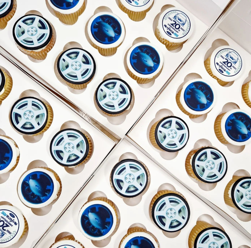 mini cupcakes in a Ford theme. Cupcakes are topped with a white butter cream icing, topped with various images such as a car wheel, steeling wheel and a logo.