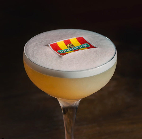 citrus foamed cocktail showing an edible image with the logo ofthe swizzels drumstick floating on the foam