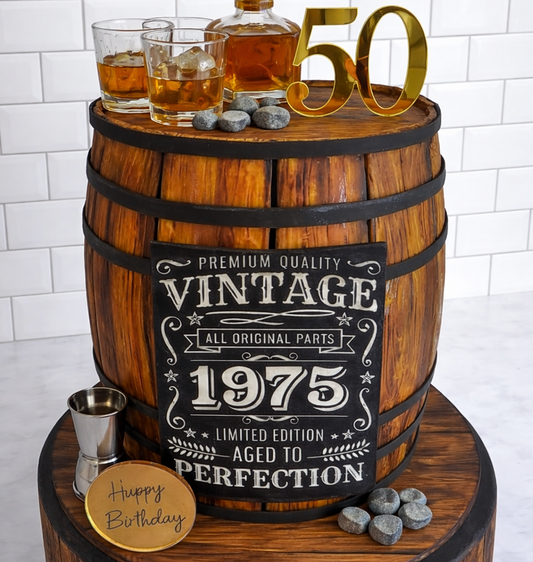 Wooden barrel cake with whiskey glasses and 'Happy Birthday' coaster, featuring a 'Vintage 1975' label.